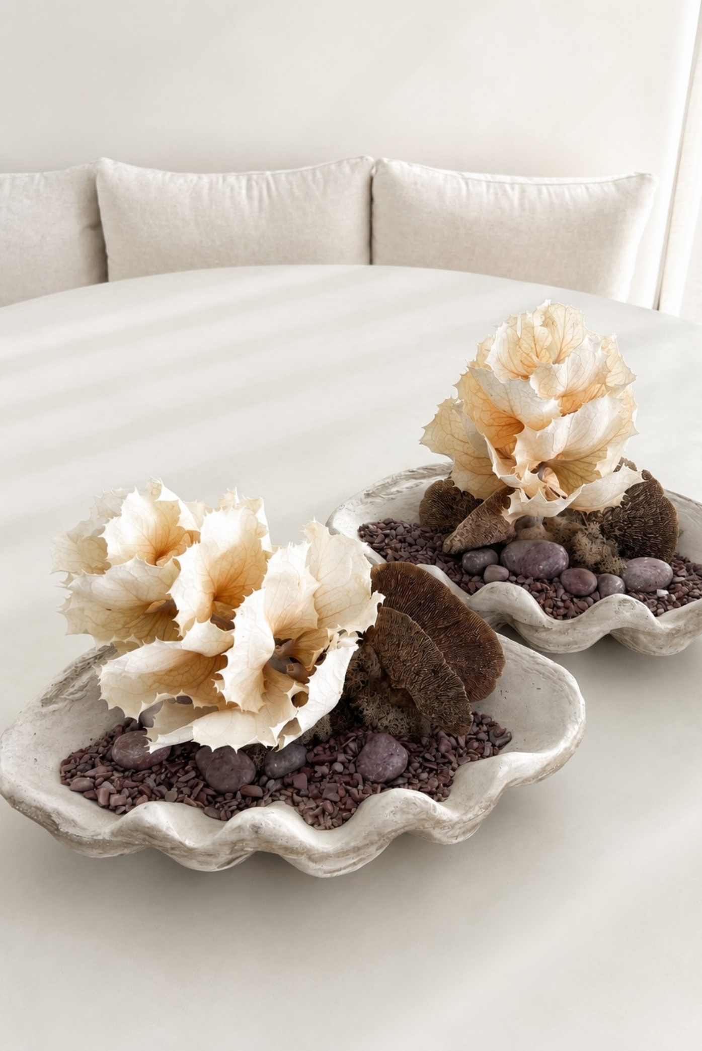 Conchas de cerámica con flores secas color crema, hongos y piedras sobre una mesa blanca