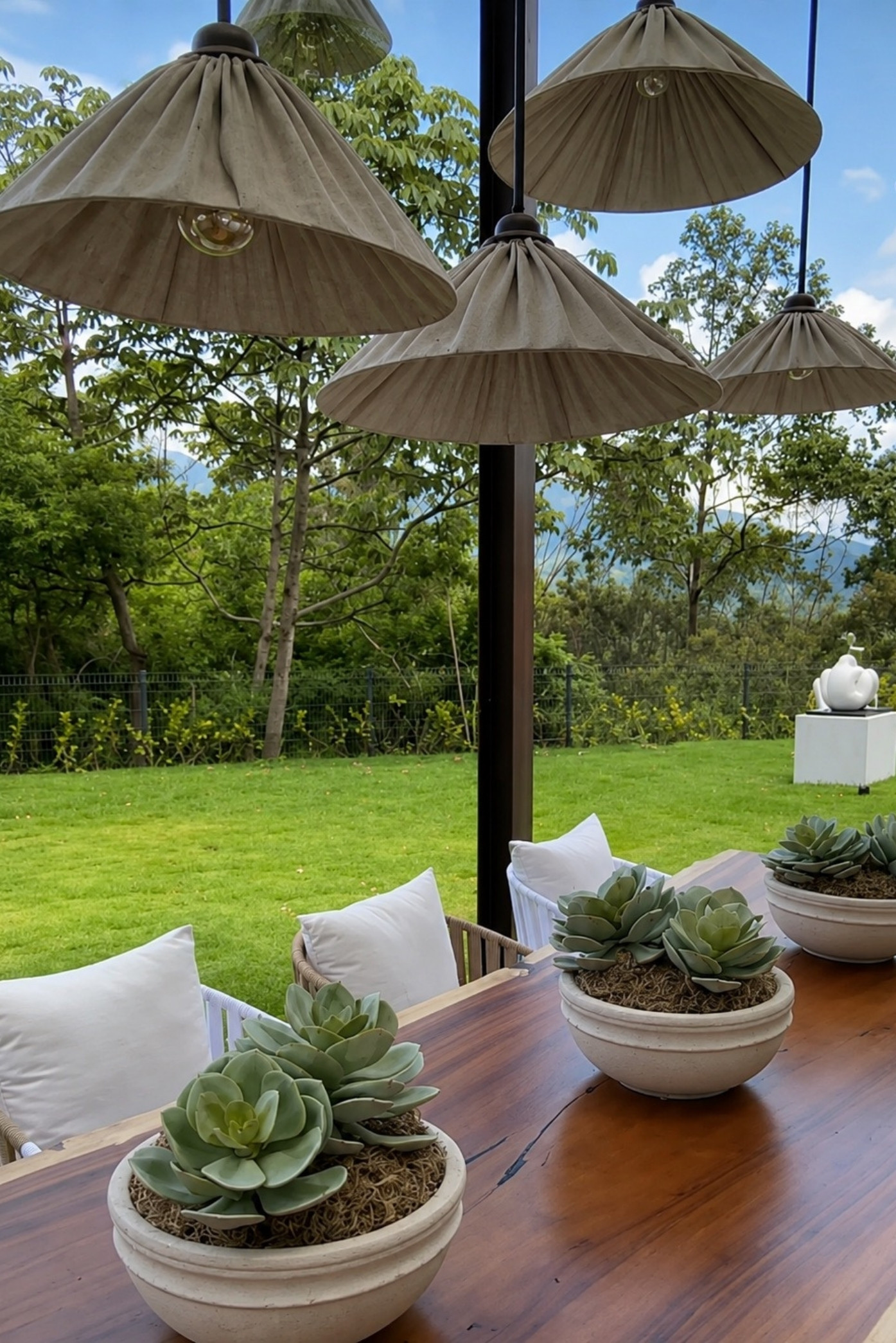 Suculentas en cuencos de piedra sobre una mesa de madera en una terraza con vista al jardín