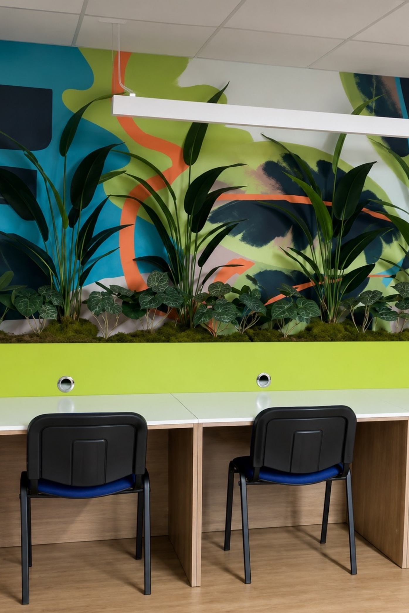 Jardinera con aves del paraíso y follajes frente a un mural de colores, sobre escritorios