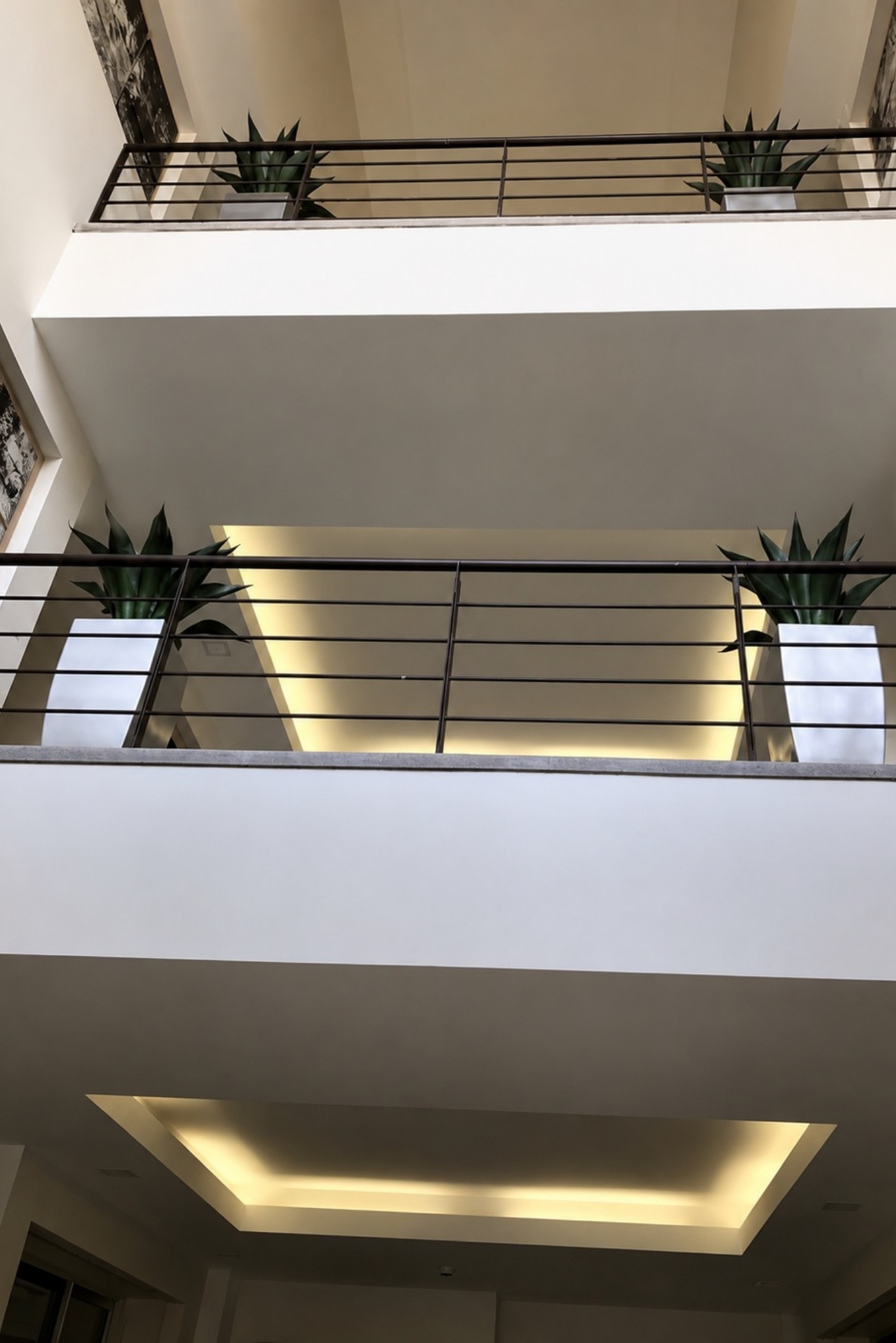 Agaves en maceteros blancos a lo largo de las barandas de dos pisos de un atrio